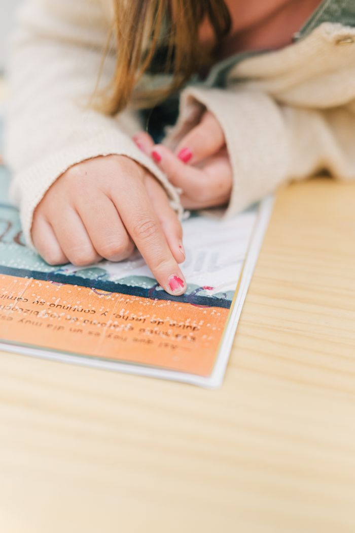 Home Childs hand reading braille text on a book, emphasizing tactile learning