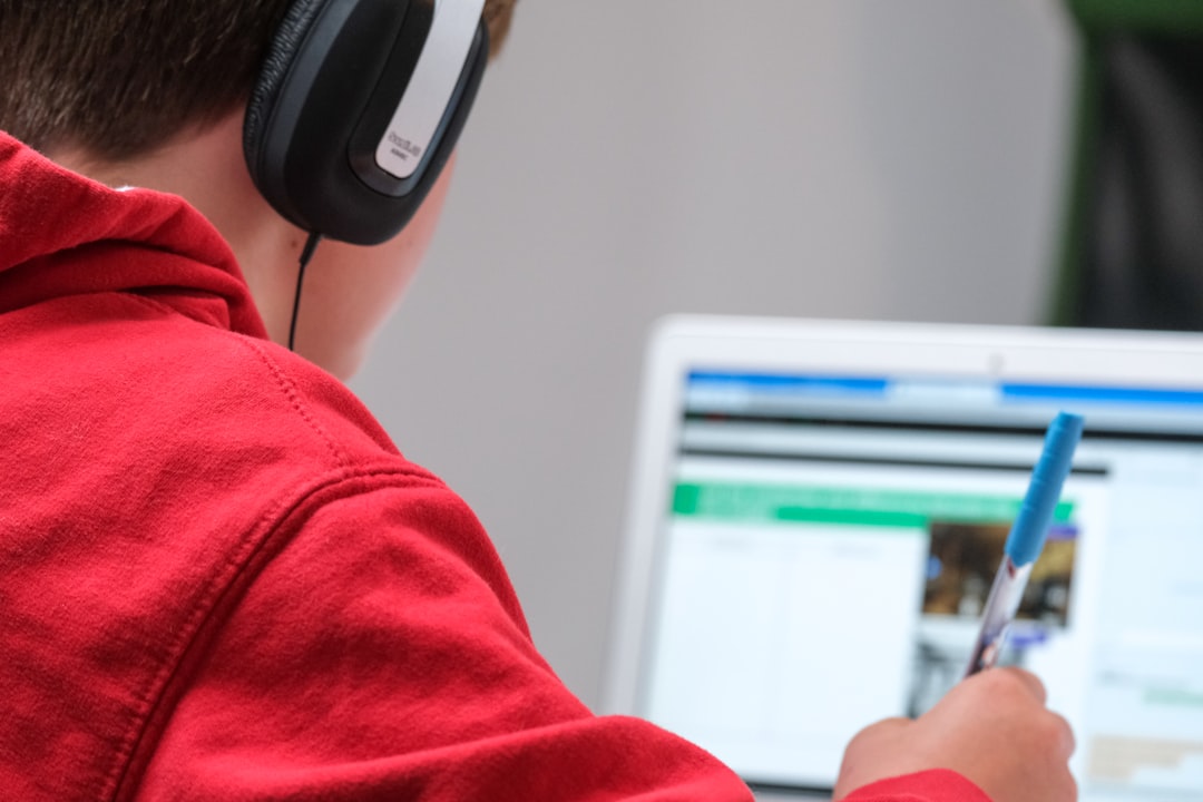 Home Home schooling during lockdown, boy working on school work with laptop and headphones during coronavirus covid 19 lock down. Remote learning through home schooling due to school closures has become commonplace in the UK in 2021.